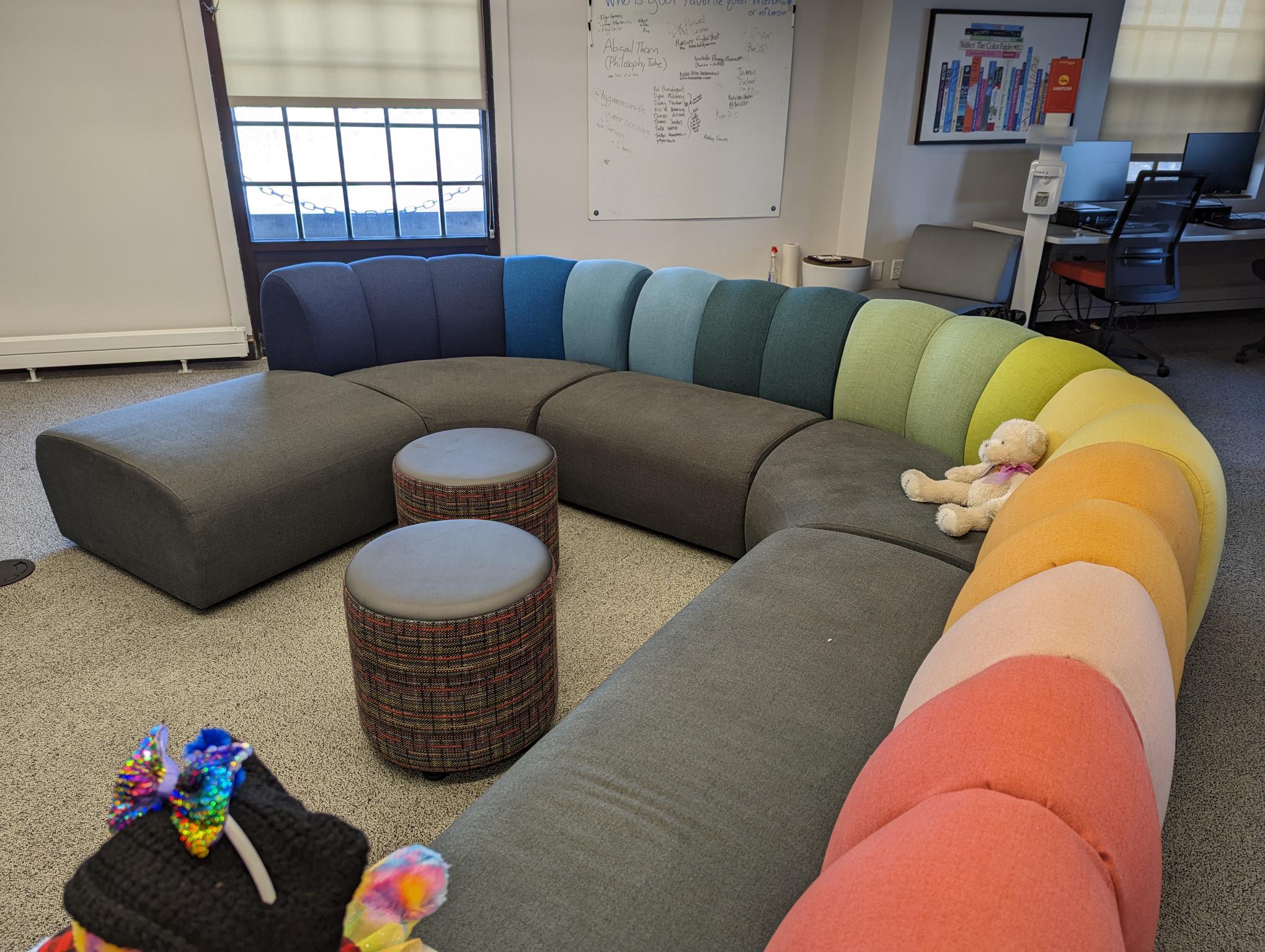 Rainbow colored couch at the center with a stuffed animal sitting on it