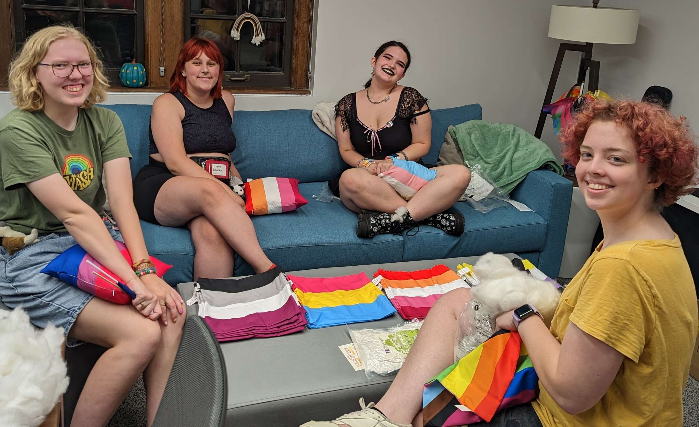 students stuffing an assortment of pride pillows on the turquoise couch