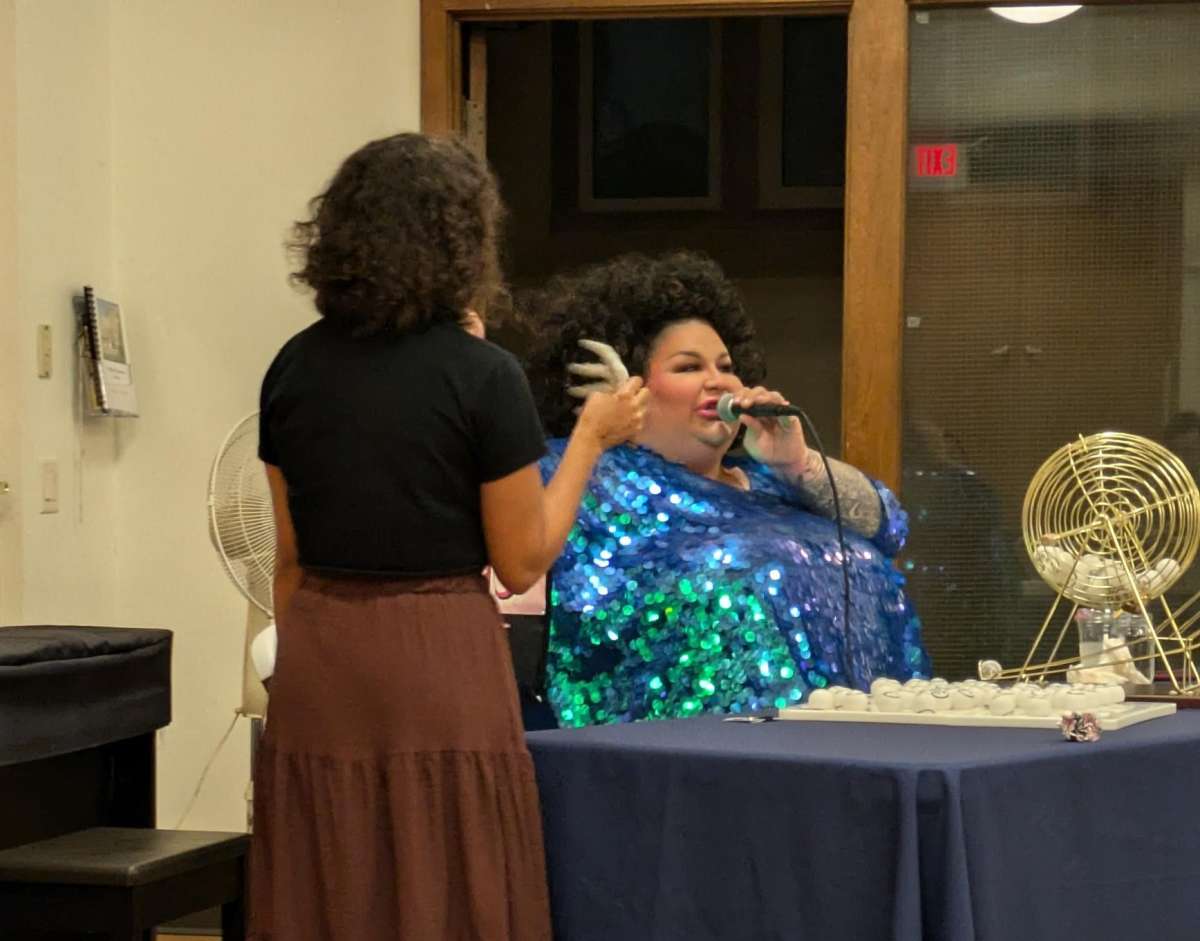 Coco the Drag Queen emceeing Drag Bingo while handing out a prize to an Iowa State student.